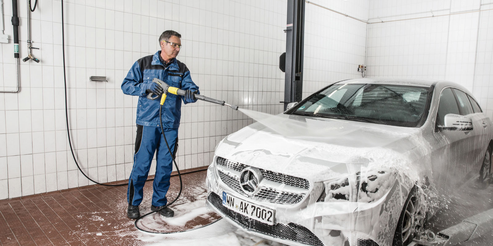 A picture of using the Kärcher hot water high-pressure cleaner HDS 10/20-4 M to clean a sedan.